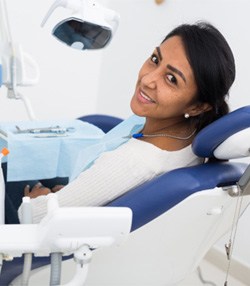 Woman looking back while sitting in dental chair and smiling 