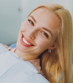 Blonde woman leaning back in dental chair and smiling  