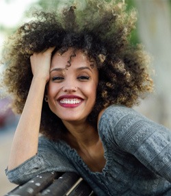 Woman sitting on a bench outside and smiling 