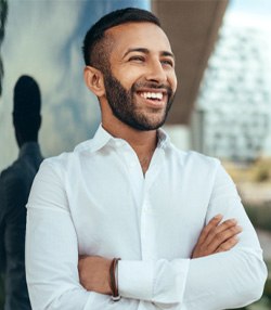 Man in white shirt smiling outside in city 