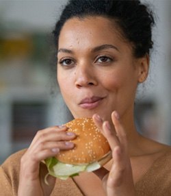 Woman holding a burger and chewing  