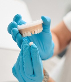 Dentist holding model of teeth and dental crown in Marshall, TX  