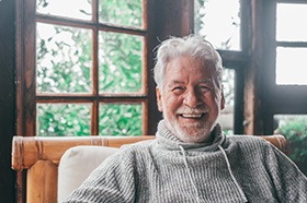 Senior man sitting in cozy cabin and smiling