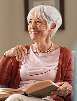 Senior woman sitting smiling at home with her implant dentures